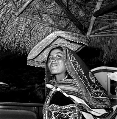 Mujer Quechua ataviada tradicionalmente en una casa rustica