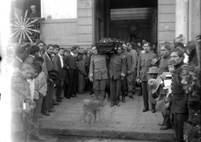 Militares con féretros en hombros, saliendo de un edificio público
