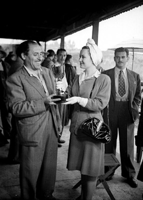 Actriz entregando trofeo a actor durante premiación de concurso de tiro, retrato