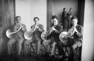 Músicos de orquesta sinfónica tocando trompas de pistones