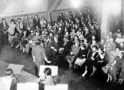 Mujer cantando ante asistentes a un programa de radio