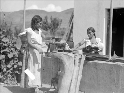 Mujeres trabajan el nixtamal en un molino manual