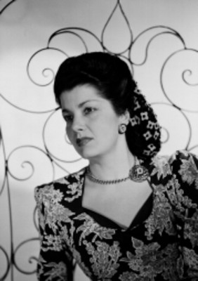Dalia Iñiguez, actriz, porta vestido floreado con escote, delante de un detalle en herreria, retrato