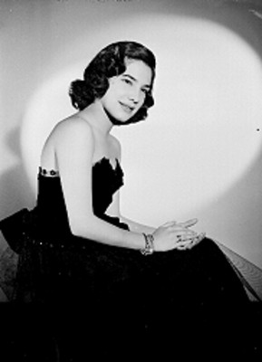 Martha Patricia, actriz, sentada con las manos unidas sobre una pierna, porta vestido de gala y accesorios, retrato de perfil