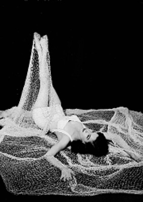 Martha Patricia, actriz, recostada sobre una red de pescar con las piernas levantadas, viste traje de baño, retrato