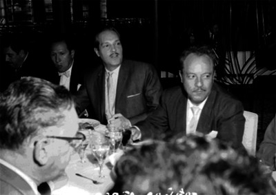 Roberto Cañedo sentado a la mesa en compañía de actores durante un banquete