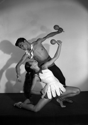 Leonor Mateos y Hugo Romero, ambos con sonajas en mano, simulan bailar, retrato de perfil