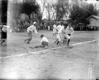 Adolescentes juegan futbol en un campo deportivo
