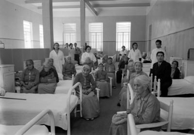 Ancianas y otras personas en el dormitorio del asilo, retrato de grupo