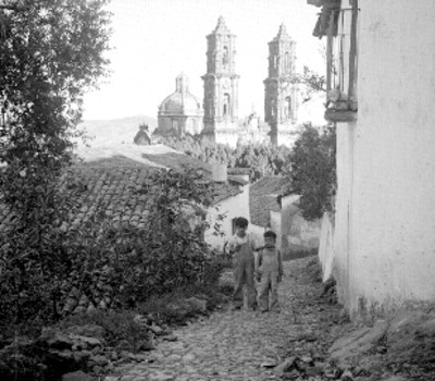 Niños en una calle, al fondo la parroquia de Santa Prisca