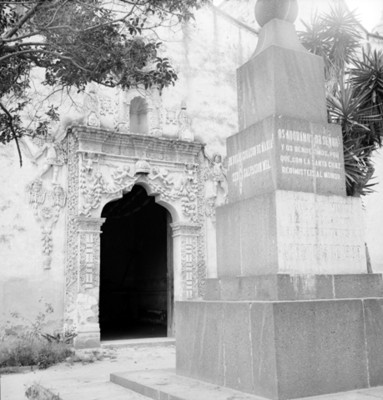 Cruz de misión frente a la entrada de un templo