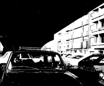 Niños a bordo de automóvil frente a edificios de unidad habitacional