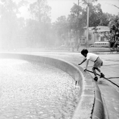 Niño juega a la orilla de una fuente