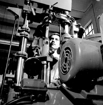 Obrero manipula maquinaria para calcular tacones en una fábrica de zapatos