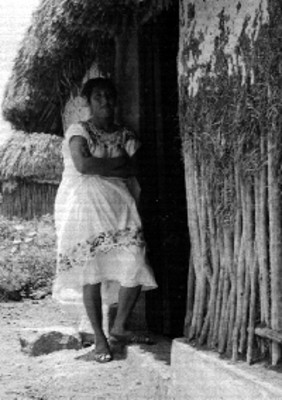 Mujer maya en la entrada de una vivienda