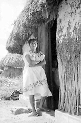 Mujer maya cerca de una casa de bajarenque