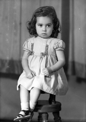 Niña sentada en un banco con las piernas cruzadas, retrato