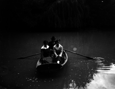 Hombre y mujeres abordo de canoa en el lago de Chapultepec