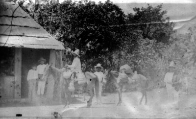 Aguadores con sus burros en patio de una casa rústica