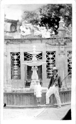 Hombre acompañado de una niña frente a una fuente, retrato