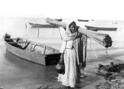 Mujer adolescente carga carrizo a la orilla del mar, retrato