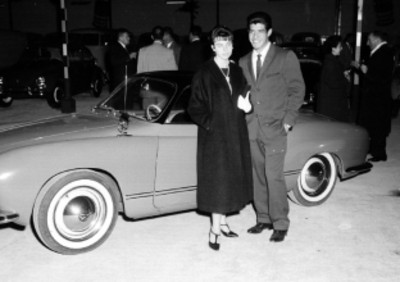 Empresario y esposa junto a un auto durante la inauguración de la organización Mexicana Automotriz