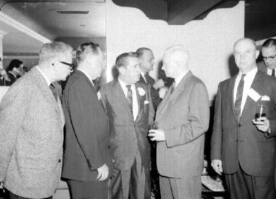 Empresarios conviviendo en un salón durante ek conktel de Commins de México