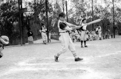 Beibolista del equipo de la General Electric bateando durante un partido en un campo deportivo