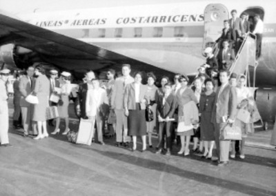 Pasajeros en las escaleras de un avión frente a este, retrato de grupo