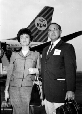 Pareja de pasajeros frente a un avión de la KLM, retrato