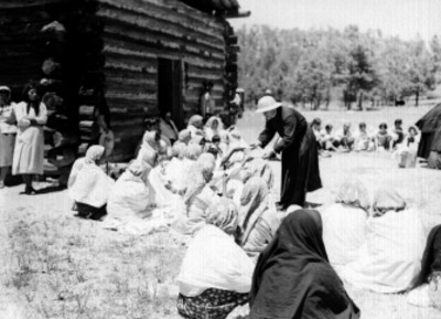 Jesuita repartiendo alimentos a Tarahumaras en el patio de una mision en Chihuahua