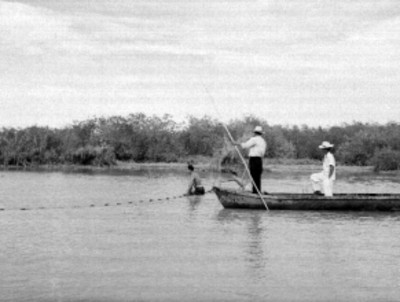 Hombres en una embarcación y pescadores trabajando, en una laguna de San Blás