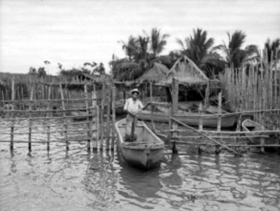 Pescador sobre una lancha saliendo de un embarcadero, en la laguan de San Blás