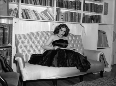 María Félix leyendo un libro en el sillón de una biblioteca, retrato