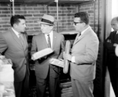 Roberto Amorós, Mariano López Mateos y hombres, observando panes elaborados por CONASUPO