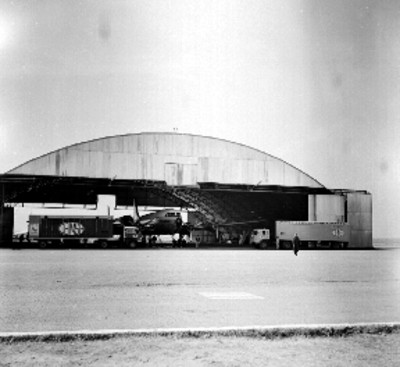 Tiendas móviles de C.E.I.M.S.A. estacionada frente a un hangar de la base aerea de Santa Lucia