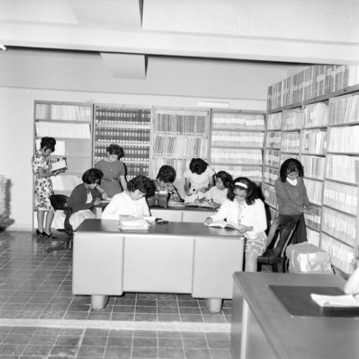 Mujeres estudiando y consultando libros, en la biblioteca de una escuela