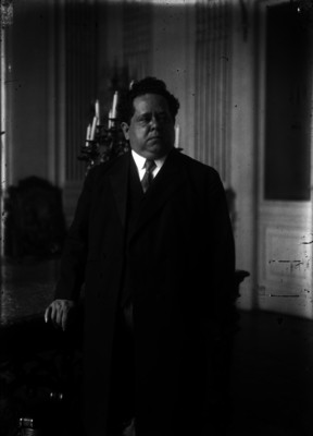 Querido Moheno, abogado y periodista parado junto a un sillón, retrato