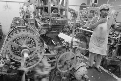 Obrero junto a maquinaria textil en la fábrica Miraflores