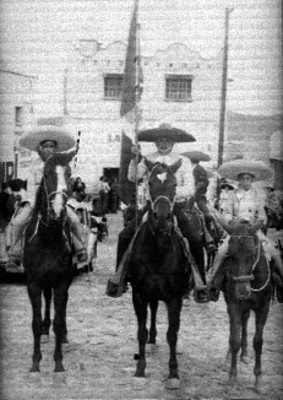 Muchachos vestidos de charro, montan a caballo por la calle, retrato de grupo