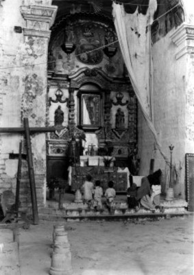 Niñas y niños hincados frente a altar religioso