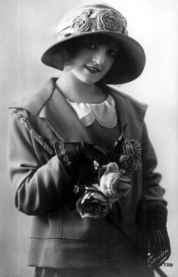 Mujer sonríe, posa con sombrero y guantes, retrato