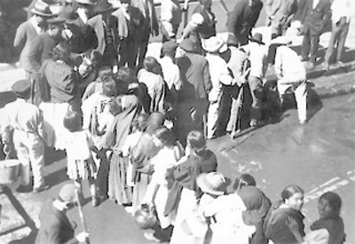 Gente haciendo fila en la calle para abastecerse de agua