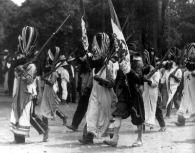 Gente con máscaras y rifles, participan en un carnaval