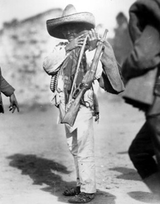 Retrato de zapatista cargando arma de fuego y sus pertenencias