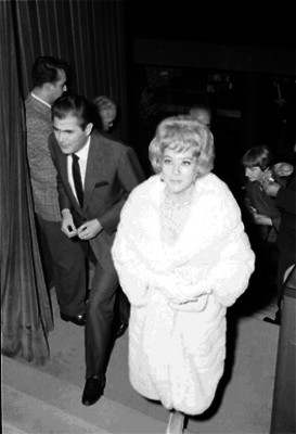 Silvia Pinal acompañada de otro actor en las escalinatas de un edificio durante un evento social