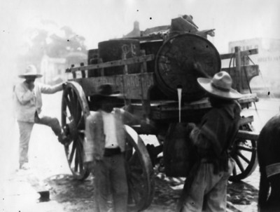 Hombre llena barril con pulque de una carreta