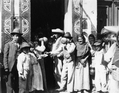 Personas consumen pulque a la entrada de una pulquería