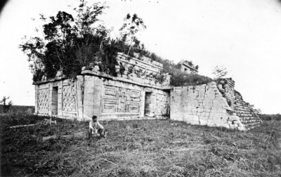 Hombre sentado junto a un edificio maya de estilo Pucc