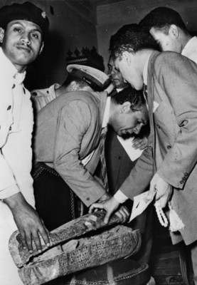 Hombres revisan pieza arqueológica